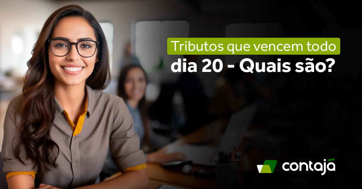 Mulher branca de cabelos castanhos, com óculos, vestindo uma camisa social cinza. Ela está com um antebraço apoiado em uma mesa. Ela está sorrindo e próximo a ela tem uma outra mulher trabalhando em um notebook. No canto direito da imagem, tem o título do artigo "Tributos que vencem todo dia 20: Quais são?"