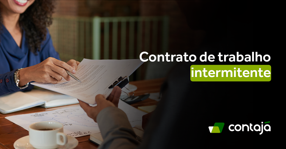 Mulher está entregando alguns documentos para um homem a sua frente. Na frente deles tem uma mesa que tem sobre papeis e uma xicara branca. No canto direito da imagem, está o título do artigo: "Contrato de trabalho intermitente"