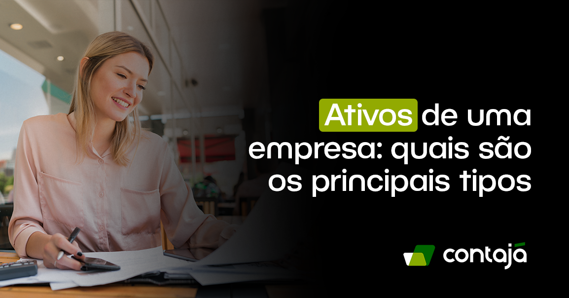 Mulher branca, com cabelo loiro, está vestindo uma camisa social rosa. Ela está sentada de frente para uma mesa de escritório. Sobre a mesa tem várias folhas de papel e uma calculadora. No canto direito da imagem, está o título do artigo: "Ativos de uma empresa: quais são os principais tipos"