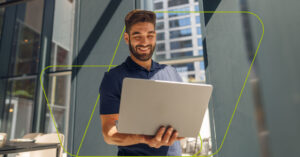 pessoa feliz em pé com notebook nas mãos