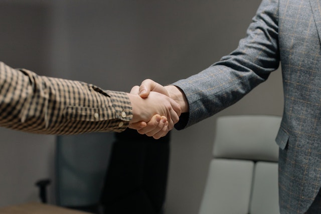 Pessoas apertando as mãos. Ambos usam roupas de manga longa. Essa imagem ilustra o artigo: "Joint Venture: O que é, Benefícios e Características."