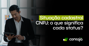 Homem branco, vestindo um blazer preto e uma camisa social branca. Ele está em pé e com uma das mãos ele está segurando um tablet. No canto direito da imagem, está o título do artigo: "Situação cadastral CNPJ: o que significa cada status?"